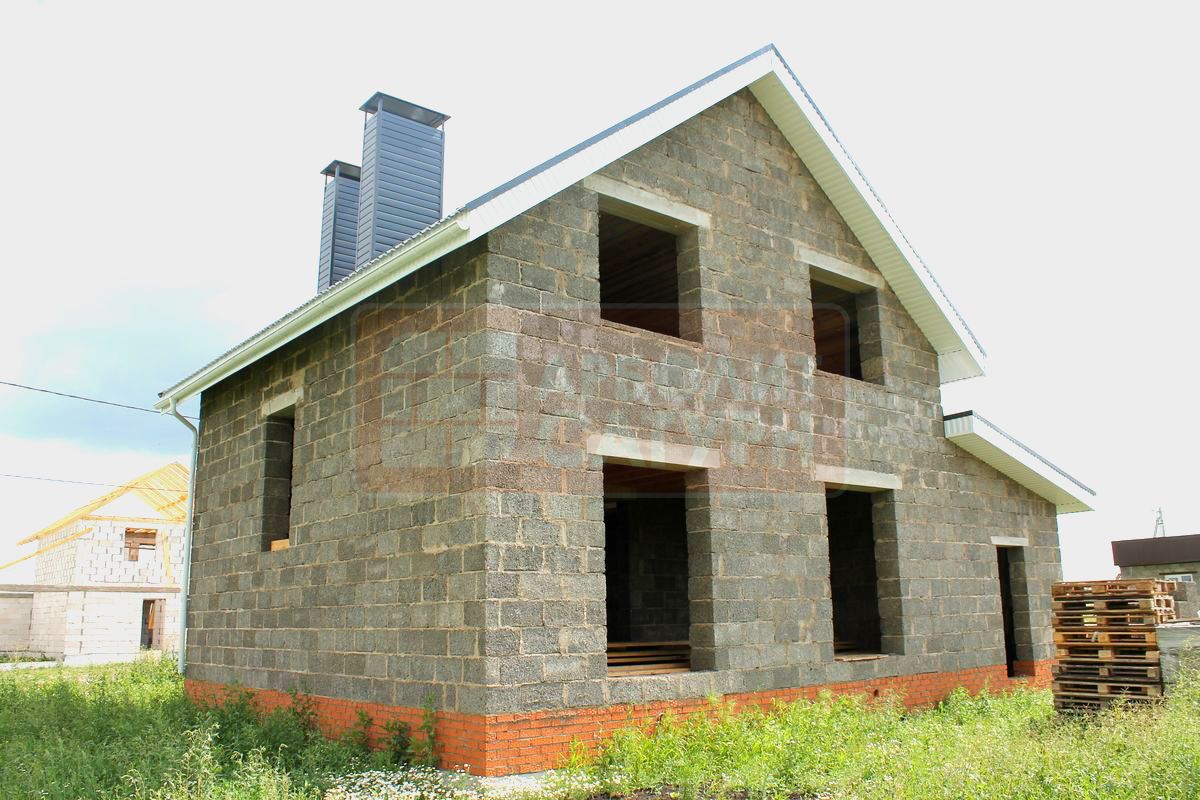 Двухэтажный дом с мансардой построенный из арболитового блока. К дому пристроен теплый гараж из арболита. Вид с торца дома.
